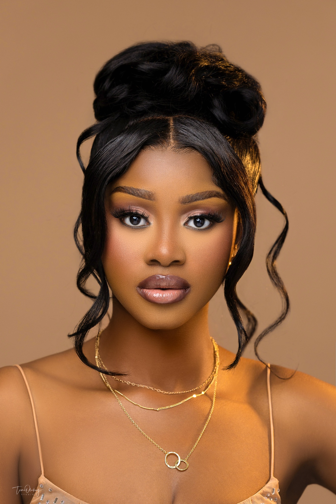 Beauty close-up with gold layered necklaces on tan backdrop
