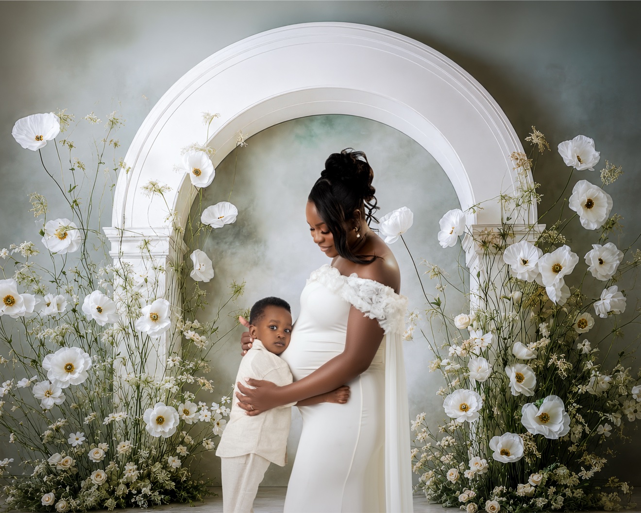 Maternity portrait with young child, white arch and white florals, white gown