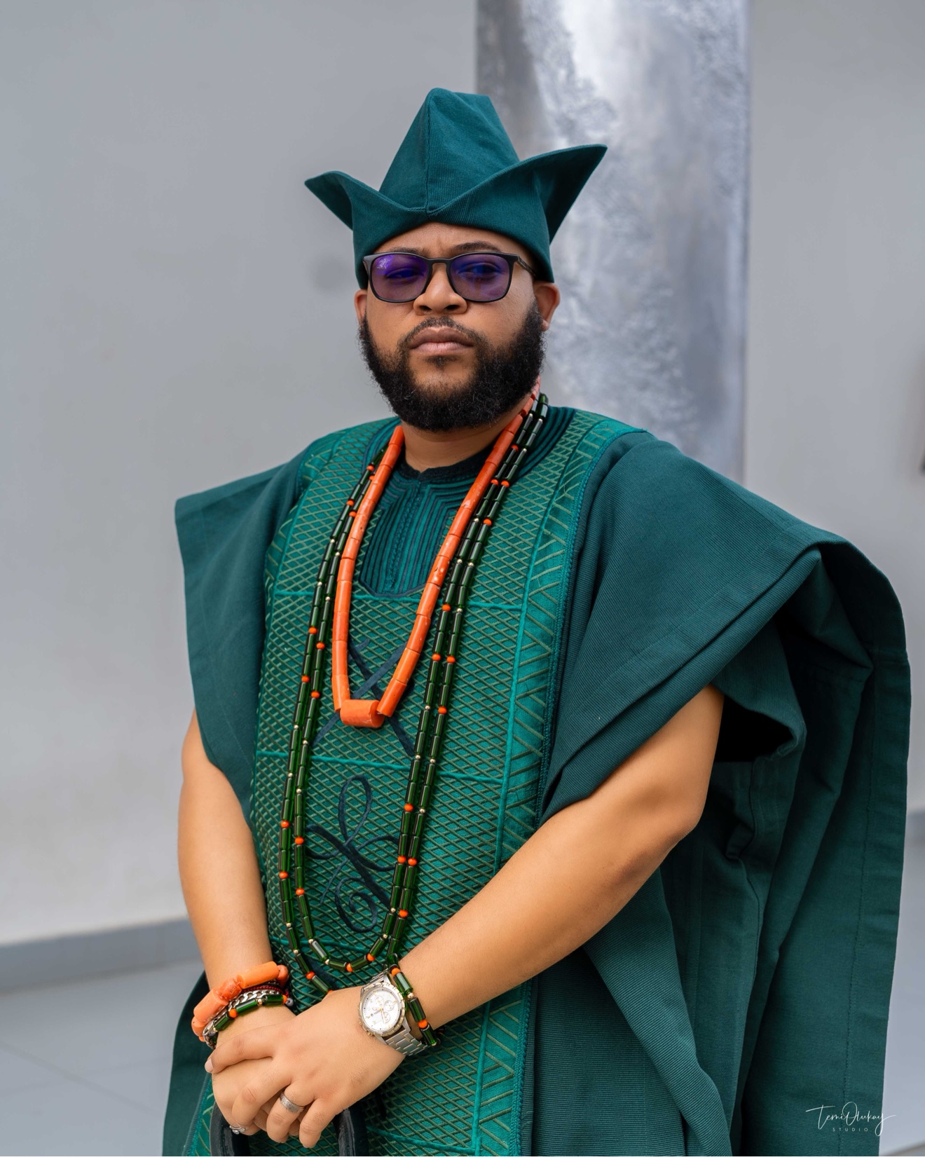 Man in a green agbada with coral bead necklaces and a green cap