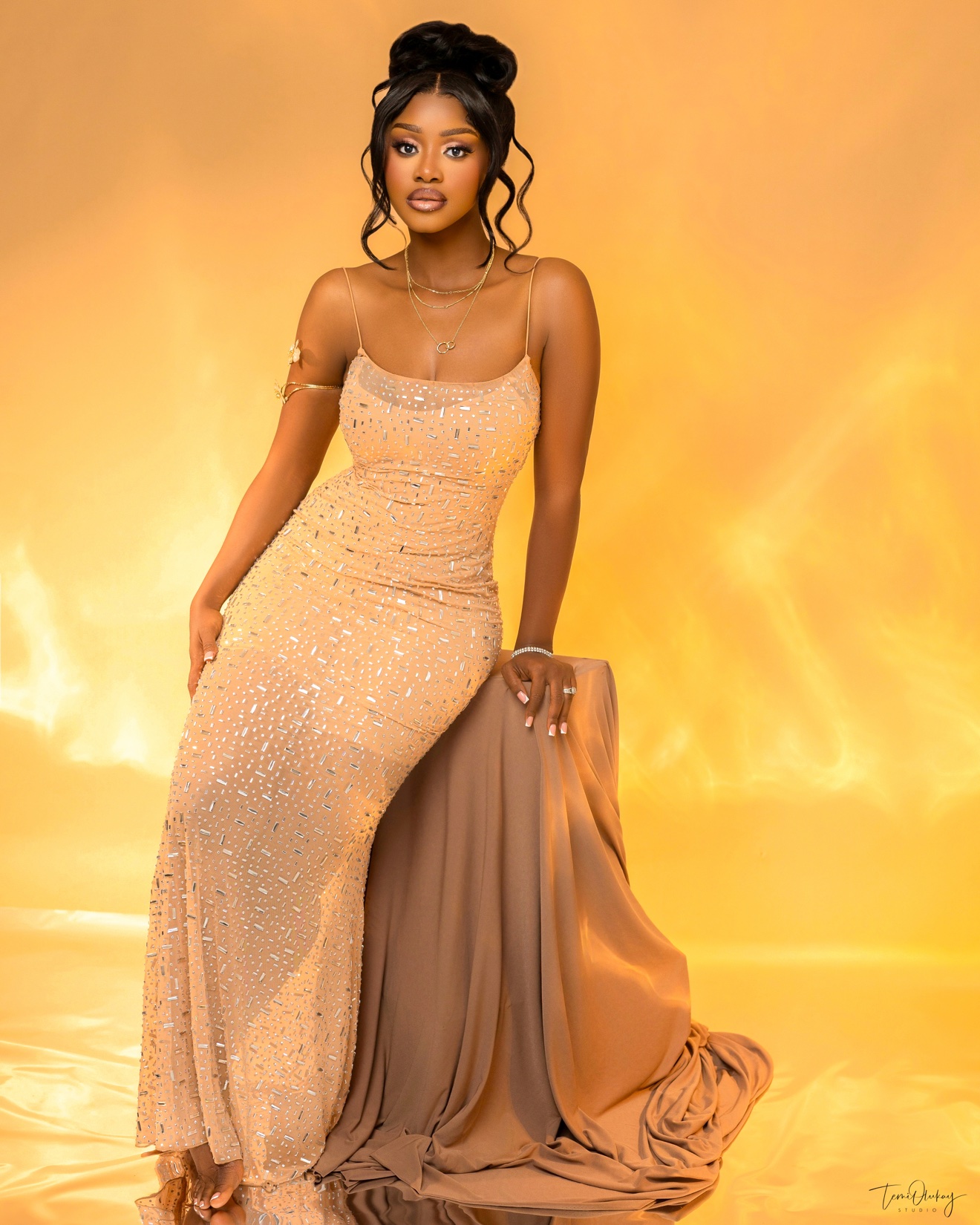 Full-length champagne beaded gown on golden backdrop