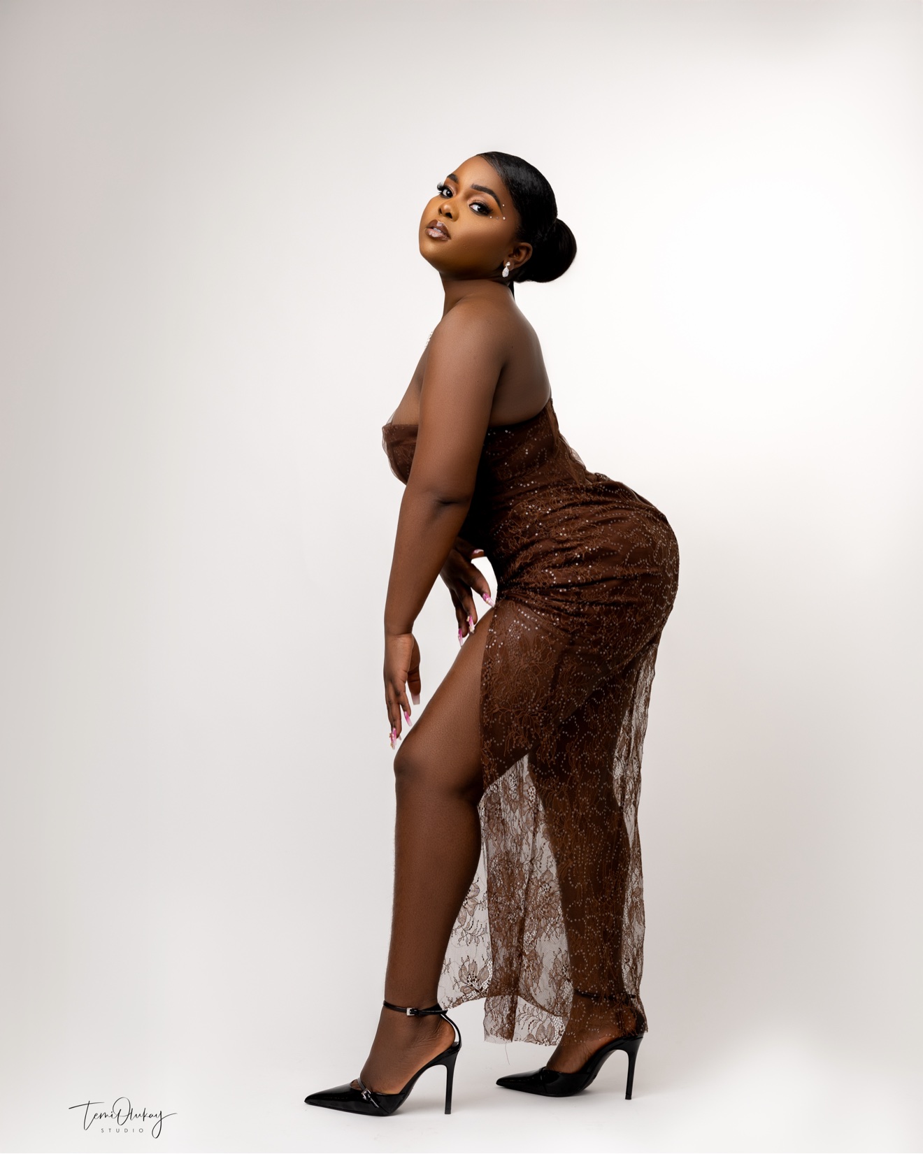 Full-length portrait in a brown lace gown on a white backdrop